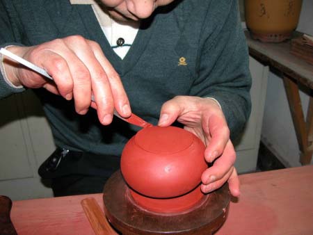 43、用“旁皮刀”挑挾起壺口裡片，塞填進壺口圈內，並用手靈巧的壓緊黏合處的圓周。